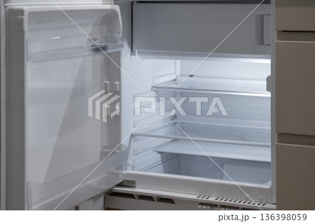 Modern open white empty refrigerator interior with bright light illuminating its adjustable shelves, representing household scarcity, a healthy diet, or fresh beginnings Modern open white empty refrigerator interior with bright light illuminating its adjustable shelves, representing household scarcity, a healthy diet, or fresh beginnings 136398059