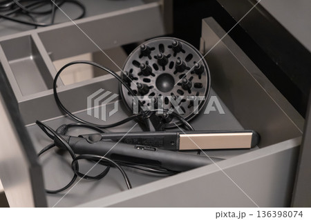 Hair straightener and dryer diffuser neatly organized in a modern gray drawer, essential tools for daily hair care, beauty routine, and efficient storage Hair straightener and dryer diffuser neatly organized in a modern gray drawer, essential tools for daily hair care, beauty routine, and efficient storage 136398074