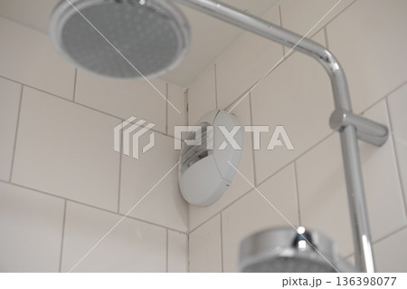 White bathroom extractor fan precisely installed in a clean tiled shower corner, ensuring efficient ventilation and fresh air circulation for a hygienic space White bathroom extractor fan precisely installed in a clean tiled shower corner, ensuring efficient ventilation and fresh air circulation for a hygienic space 136398077
