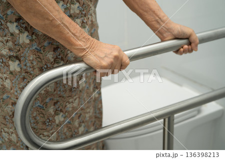 Asian elderly woman patient use handrail safety in toilet support rail in bathroom. 136398213