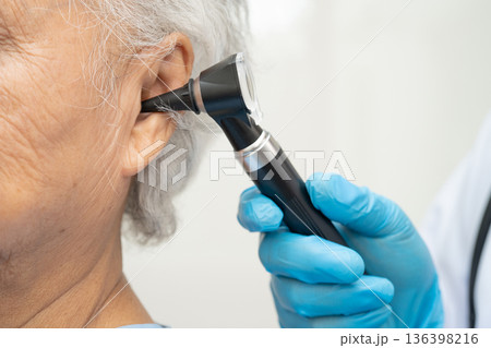 Otolaryngologist or ENT physician doctor examining senior patient ear with otoscope, hearing loss problem. Otolaryngologist or ENT physician doctor examining senior patient ear with otoscope, hearing loss problem. 136398216
