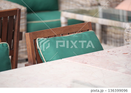 Outdoor seating area with green cushions and marble table 136399096