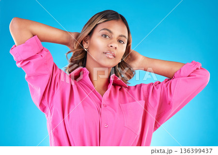 Woman, confident portrait and fashion in studio for beauty, cosmetics and natural makeup. Young Indian female model person with hands behind head on blue background with casual style clothes and glow 136399437