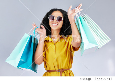Sunglasses, portrait and woman with shopping bag for fashion in studio isolated on a white background. Face smile, sales and African customer with gift, discount deal and clothes from retail store Sunglasses, portrait and woman with shopping bag for fashion in studio isolated on a white background. Face smile, sales and African customer with gift, discount deal and clothes from retail store 136399741