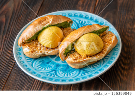 Authentic Vada Pav Indian street food with spicy chutney on rustic wooden background Authentic Vada Pav Indian street food with spicy chutney on rustic wooden background 136399849