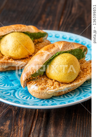Authentic Vada Pav Indian street food with spicy chutney on rustic wooden background 136399851