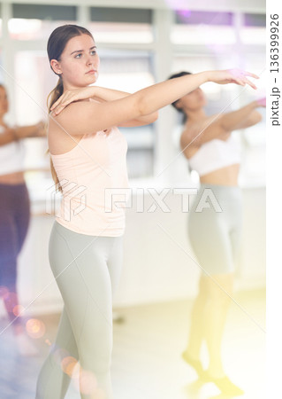 Beautiful young girl student ballet school training various ballet position during warm-up sessions in sports hall together Beautiful young girl student ballet school training various ballet position during warm-up sessions in sports hall together 136399926