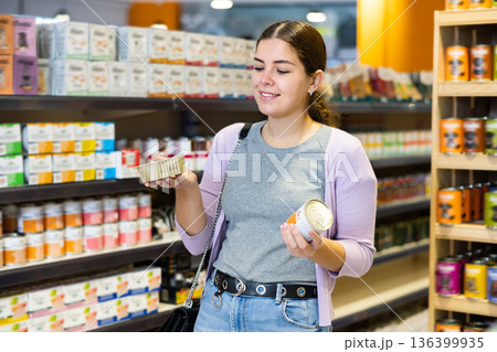 Young woman choosing canned dog food in pet store 136399935