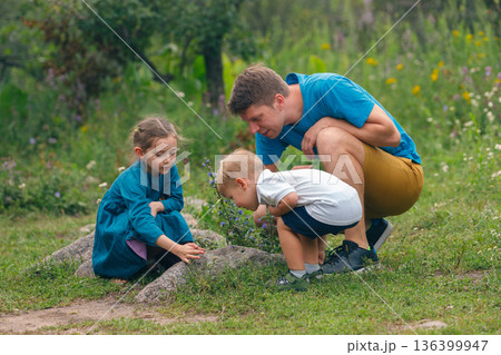 A loving family is having a wonderful time together while they explore the beauty of nature in a lush green setting A loving family is having a wonderful time together while they explore the beauty of nature in a lush green setting 136399947