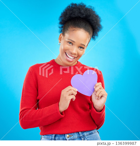Woman, portrait and heart cut out with a smile for love and valentines day in studio. African female person, blue background and romance emoji icon for kindness with a young happy model and paper Woman, portrait and heart cut out with a smile for love and valentines day in studio. African female person, blue background and romance emoji icon for kindness with a young happy model and paper 136399987