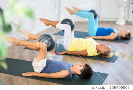 Positive preteen boy practicing lying fitness pose with softball between legs 136400002