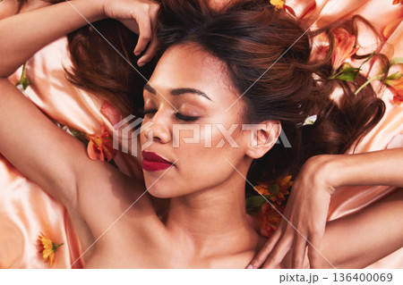 Top view, cosmetics and woman in bed with flowers for glow or dermatology with luxury facial. Cosmetology, beauty and face with girl wearing makeup for natural grooming or self care for spa treatment 136400069