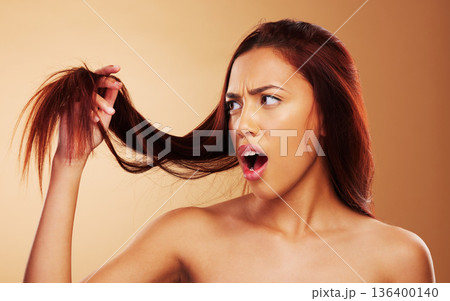 Hair, damaged and a woman in studio for salon, hairdresser and split end treatment. Stress, upset and shocked aesthetic model person with dry texture or worry hairstyle crisis on a brown background Hair, damaged and a woman in studio for salon, hairdresser and split end treatment. Stress, upset and shocked aesthetic model person with dry texture or worry hairstyle crisis on a brown background 136400140