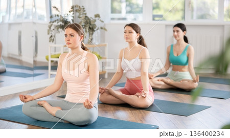 Meditation in lotus position during yoga class in studio. Women meditating Meditation in lotus position during yoga class in studio. Women meditating 136400234
