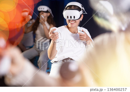 Young woman immersed in virtual reality game in gaming center Young woman immersed in virtual reality game in gaming center 136400257