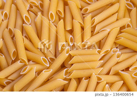 Closeup of penne pasta textures, Macro image highlighting golden segmented pasta, Highresolution photograph emphasizing detailed semolina surfaces and golden ridges of pasta 136400654