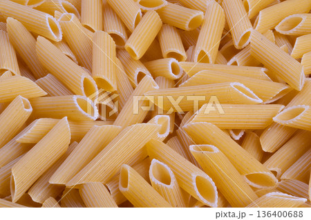 Closeup artisan penne cluster evokes rustic handcrafted production, ridged tubular shapes and warm golden hues, intimate studio lighting for craft pasta branding 136400688