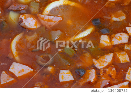 Hearty solyanka simmering on stove with chunks of cured meats, olive slices, paprika flecks and soft potato, steam rising, mood of busy home cook prepping simple nourishing dinner Hearty solyanka simmering on stove with chunks of cured meats, olive slices, paprika flecks and soft potato, steam rising, mood of busy home cook prepping simple nourishing dinner 136400785