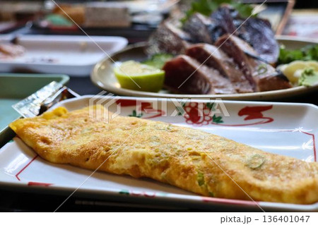 食卓に並ぶだし巻き卵とカツオのたたき 136401047