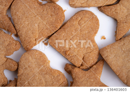 Heart and star gingerbread cookies arranged on white surface, warm brown texture, visible crumbs, closeup flatlay evoking home kitchen comfort and rustic baking tradition 136401603