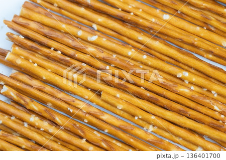 Salted pretzel sticks arranged neatly. Crunchy pretzels with coarse salt in orderly rows. Golden crisp pretzels sprinkled with salt crystals on plain background Salted pretzel sticks arranged neatly. Crunchy pretzels with coarse salt in orderly rows. Golden crisp pretzels sprinkled with salt crystals on plain background 136401700