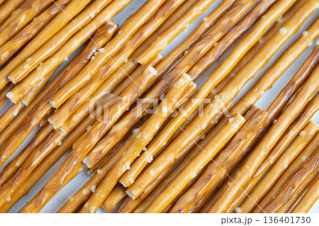 Large saltcoated pretzel sticks organized for sale and display. Extensive arrangement of pretzel sticks with coarse salt designed for online and instore showcases 136401730