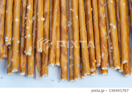 Snack moment broken pretzel ends scattered on pale surface, crumb fragments, coarse salt crystals, casual comfort food vibe, handheld snack suggestion, textured closeup 136401767