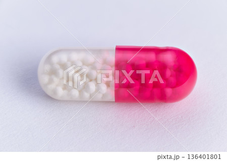 Pink capsule details. Translucent pink capsule under light. Laboratory illuminated pink capsule with granules. Laboratory testing shows pink capsule with granules and translucency 136401801