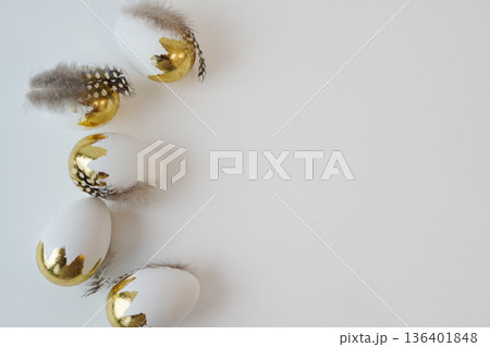Elegant white Easter eggs decorated with gold leaf and feathers 136401848