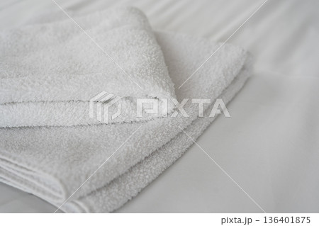 Clean folded white towels on hotel bed in bright room 136401875