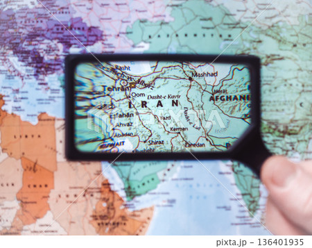 Male hand holds magnifying glass over world map Male hand holds magnifying glass over world map 136401935