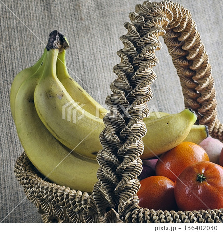 Woven straw basket on a burlap background. Close-up. Details. Eco-friendly. The handmade basket is filled with fruit 136402030