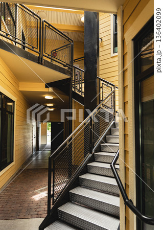 A staircase leading up in residential building with yellow exterior. The stairs are made of metal. A staircase leading up in residential building with yellow exterior. The stairs are made of metal. 136402099