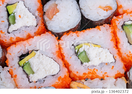 Gourmet sushi presentation. Luxury sushi with toppings. Elegant sushi roll with vibrant colors and textures. Upscale sushi arrangement featuring avocado and tobiko accents 136402372
