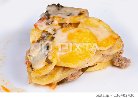 Leftover potato casserole portion on plate, slightly compacted slice with cooled cheese edges and scattered crumbs, realistic leftover vibe for meal prep and budget cooking themes Leftover potato casserole portion on plate, slightly compacted slice with cooled cheese edges and scattered crumbs, realistic leftover vibe for meal prep and budget cooking themes 136402430