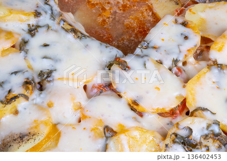 Mozzarella melts over crispy potato slices. Golden crust topped with herbs and shiny oil finish. Deliciously cheesy potato with melted cheese over crispy slices and herb seasoning 136402453