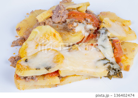 Golden cheesy potato. Baked potato slices with cheese. Closeup of crispy cheesy potato slices. Studio shot highlighting golden crust with herbs and melted cheese 136402474