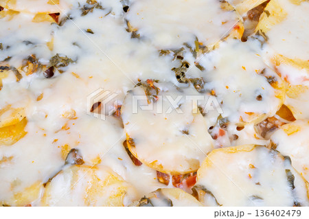 Cheese potato delight. Creamy potatoes with herb topping. Cheeseladen potato slices with garnished herbs. Melted cheese over potatoes complemented by herbs for celebration 136402479