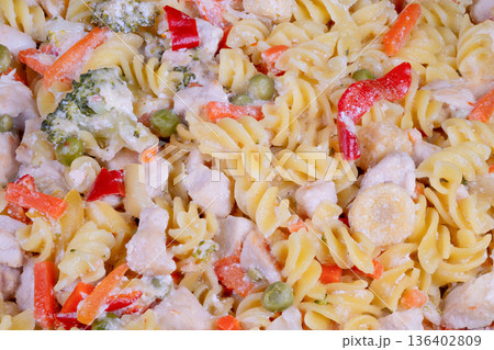 Creamy pasta bowl with colorful vegetables soft spirals bitesized broccoli sweet peas tender carrot strips mild seasoning casual family table parent serving kids 136402809