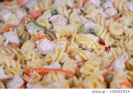 Photograph displaying fusilli with various diced vegetables. Vibrant food photography of fusilli pasta with mixed diced chicken and fresh vegetables for advertising 136402914