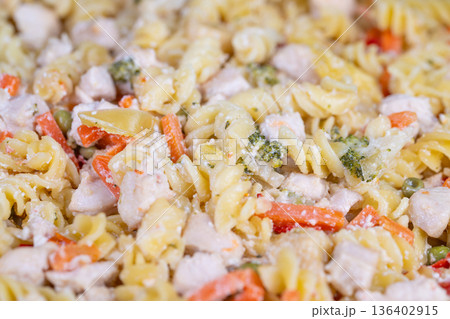 Delicious creamy pasta salad combined with colorful vegetables and chicken pieces. Savory dish of smooth creamy pasta tossed with fresh vegetables and tender chicken chunks 136402915