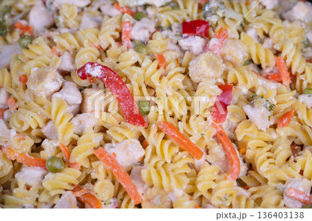 Family pasta gathering. Warm communal serving of pasta. Sharing cozy bowl of creamy pasta and vegetables. Homey scene with family enjoying creamy pasta and mixed vegetables 136403138