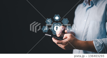 person use smartphone with glow finance icons including dollar symbol, piggy bank, calendar, savings, and analytics, symbolizing digital banking, money management, financial planning, and investment. 136403293