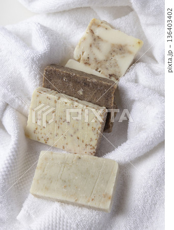 Unbranded beige and brown solid soap bars on white terry towel, bathroom spa amenities Unbranded beige and brown solid soap bars on white terry towel, bathroom spa amenities 136403402
