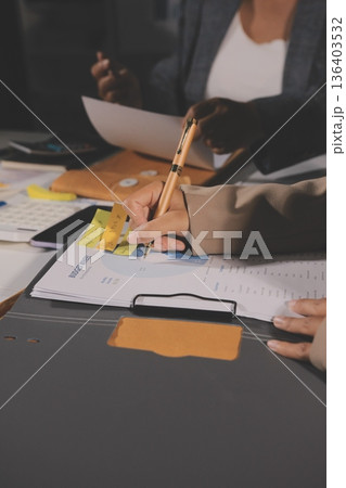 business documents on office table with tablet, smart phone and laptop and two colleagues discussing data business documents on office table with tablet, smart phone and laptop and two colleagues discussing data 136403532