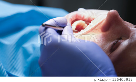 Dental care procedure featuring a calm patient in a clinical setting during a bright afternoon Dental care procedure featuring a calm patient in a clinical setting during a bright afternoon 136403915