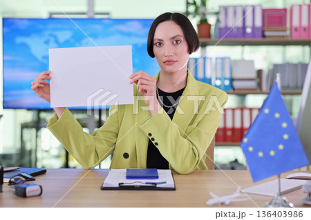 Confident business professional displays blank document in a modern office setting during a productive workday 136403986
