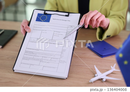 Preparing for a journey with a Schengen visa application at a wooden table in a bright, modern office setting Preparing for a journey with a Schengen visa application at a wooden table in a bright, modern office setting 136404008