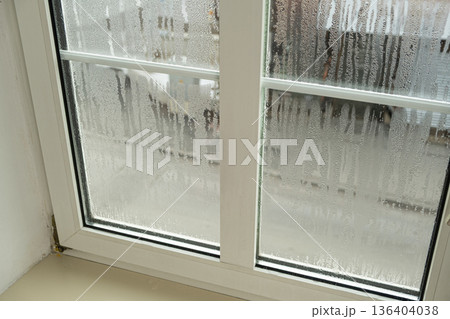 Close up of misted window glass with water streaks and droplets 136404038