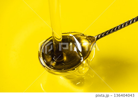Pouring extra virgin olive oil into silver spoon 136404043